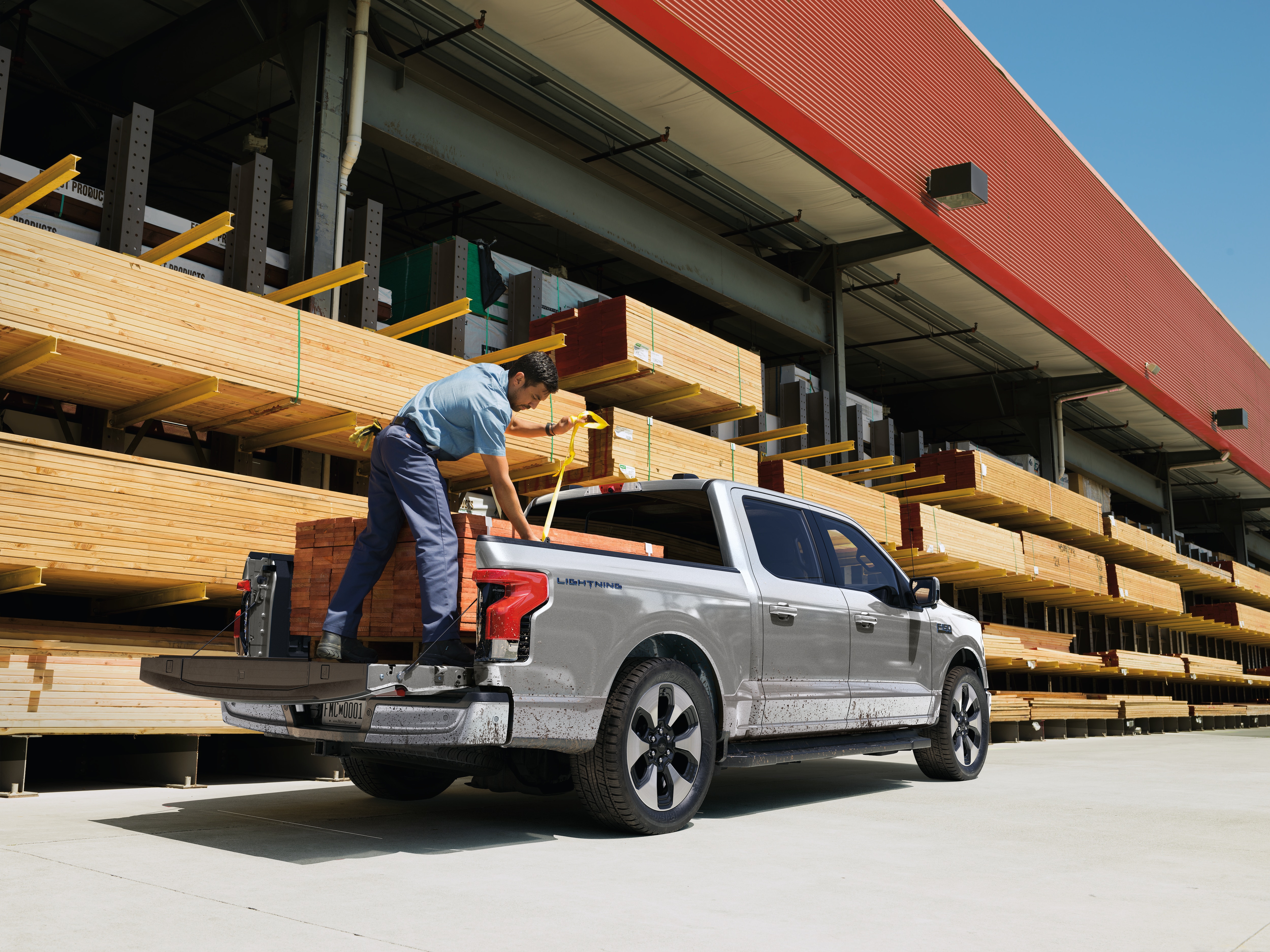 A man loads wood into the bed of a truck.